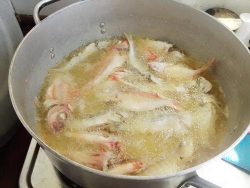 Faire frire du poisson frais à bord d'un gozzo alla Maddalena en bois