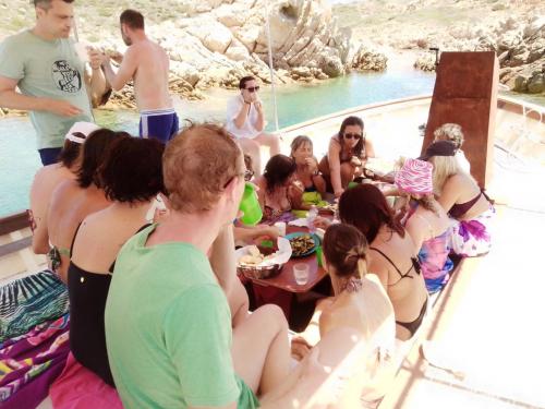 Group of hikers have lunch on board a wooden gozzo during excursion to Maddalena