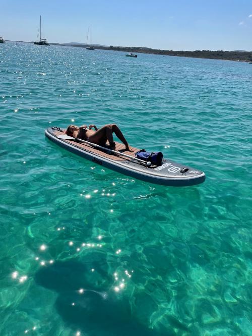 Une jeune fille se détend en SUP dans les eaux du nord-est de la Sardaigne