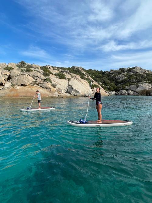 Freunde auf einem SUP-Ausflug bei Sonnenuntergang im Meer an der Costa Smeralda