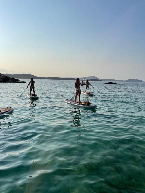 Freunde auf einem SUP-Ausflug bei Sonnenuntergang im Meer an der Costa Smeralda