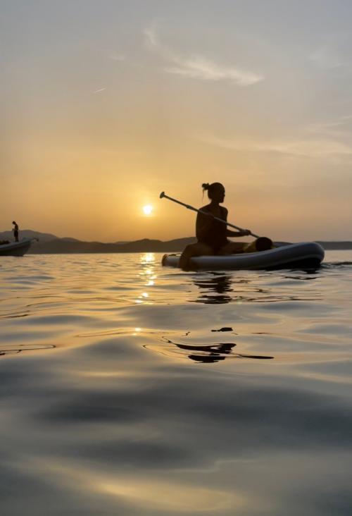 Mädchen bei einem SUP-Ausflug bei Sonnenuntergang im Meer der Costa Smeralda