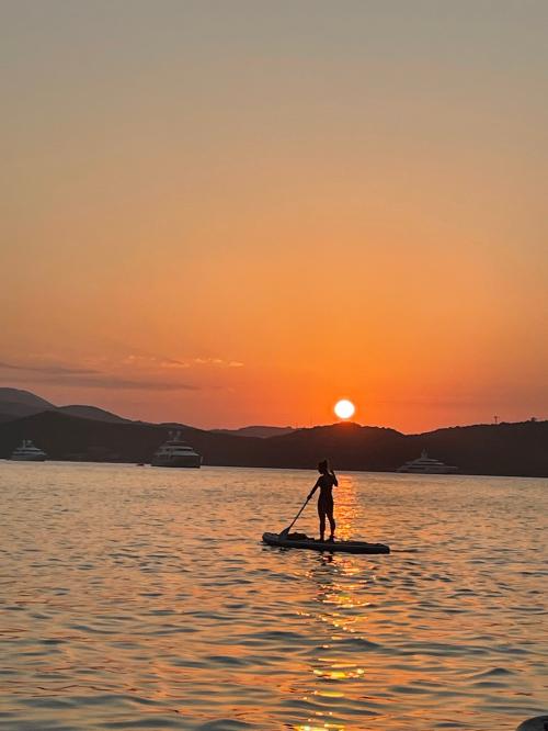 girl on a SUP excursion at sunset in the sea of the Costa Smeralda