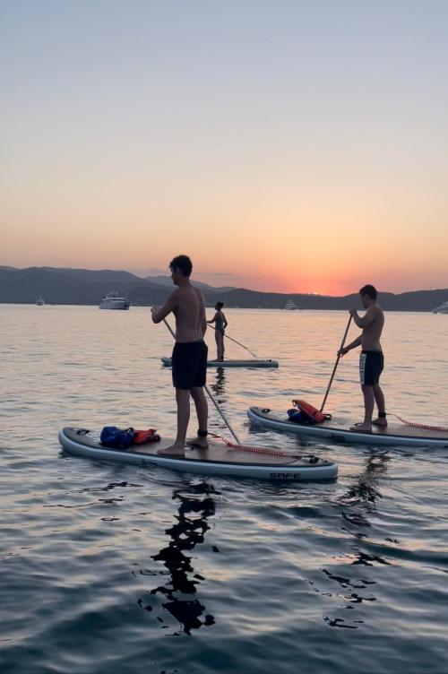 Freunde auf einem SUP-Ausflug bei Sonnenuntergang im Meer an der Costa Smeralda