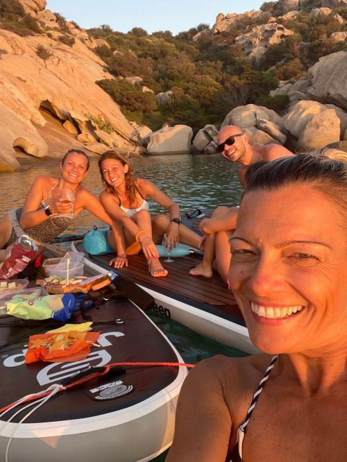 Freunde auf einem SUP-Ausflug bei Sonnenuntergang im Meer an der Costa Smeralda