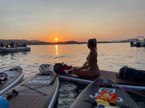Mädchen bei einem SUP-Ausflug bei Sonnenuntergang im Meer der Costa Smeralda