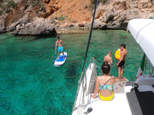 Junge auf SUP und Passagiere an Bord eines Katamarans