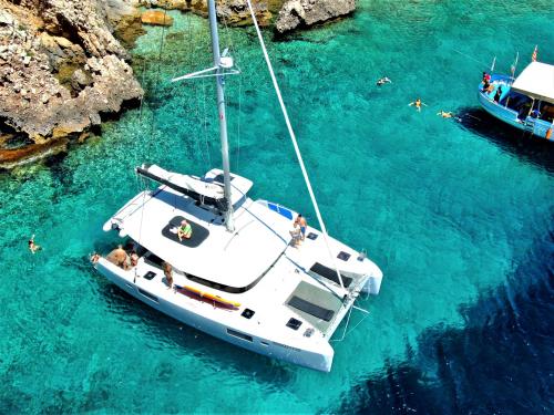 Excursionistas nadan durante un día en el mar de Alghero a bordo de un catamarán