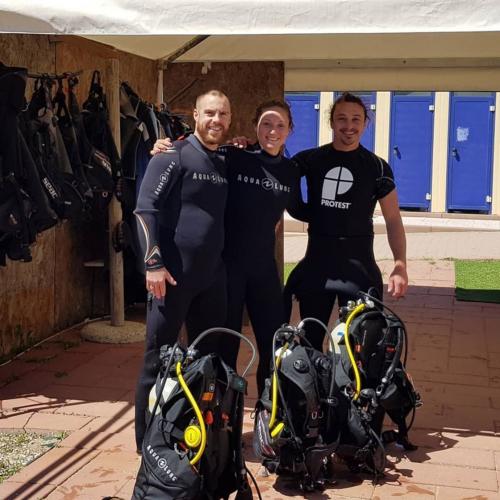 Guía y excursionistas preparan el equipo para el bautismo de buceo.