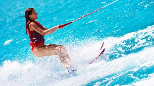 Mädchen im kristallklaren Meer Sardiniens beim Wasserskifahren
