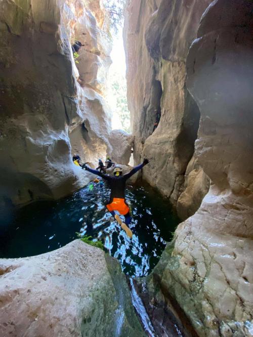 A hiker plunges into the water during a guided canyoning excursion