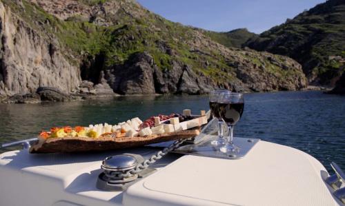 Calice di vino e salumi con formaggi serviti a bordo di un gommone durate escursione giornaliera nel sud ovest Sardegna