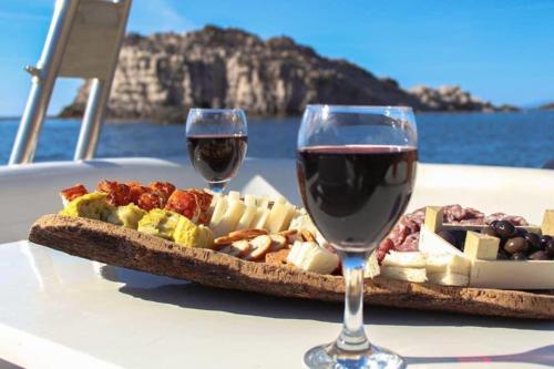Calice di vino e salumi con formaggi serviti a bordo di un gommone durate escursione giornaliera nel sud ovest Sardegna