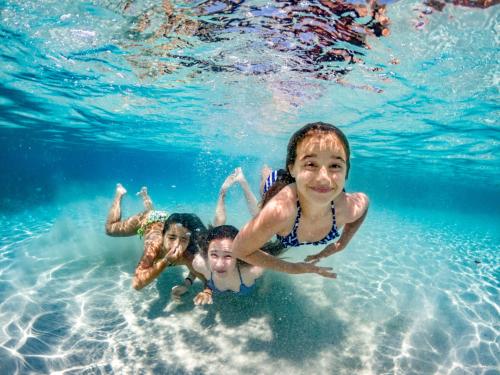 Kinder schwimmen während eines Stopps im türkisfarbenen Wasser des La-Maddalena-Archipels