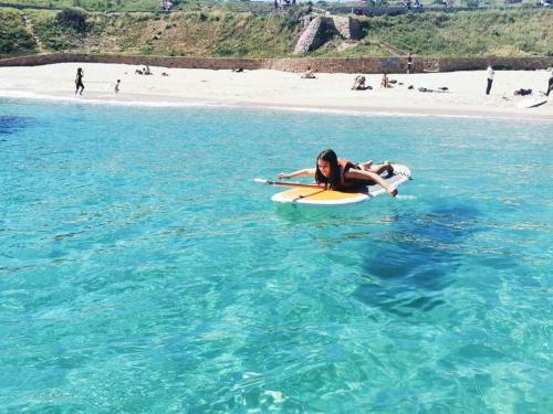 Mädchen versucht zum ersten Mal SUP am Strand von Porto Torres