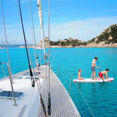 Family in sup during mini cruise on a sailboat in Sardinia