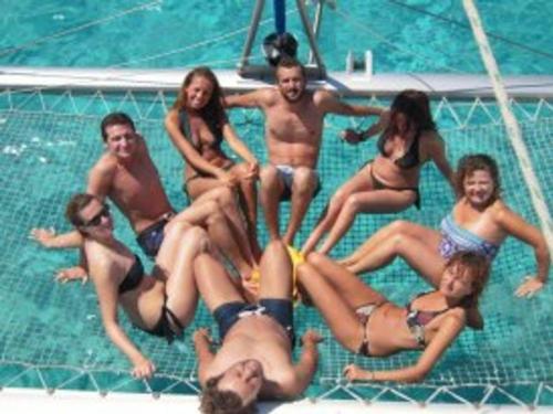 Menschen auf dem Sonnendeck des Katamarans beim Segeln im Archipel von La Maddalena