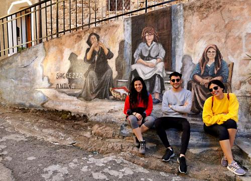 Groupe de randonneurs avec des peintures murales d’Orgosolo en arrière-plan pendant la visite guidée