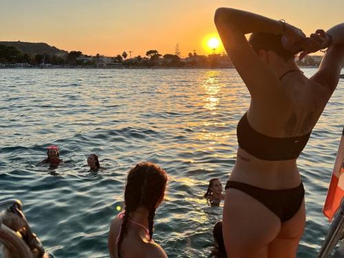 Ragazzi fanno il bagno al tramonto da una barca a vela nella costa di Cagliari