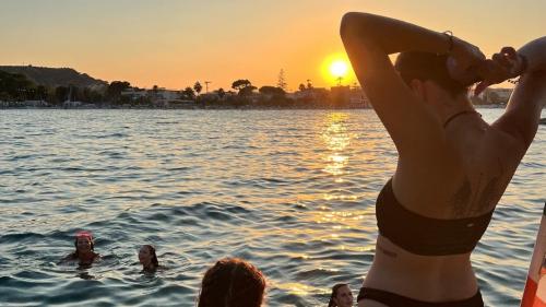 Ragazzi fanno il bagno al tramonto da una barca a vela nella costa di Cagliari