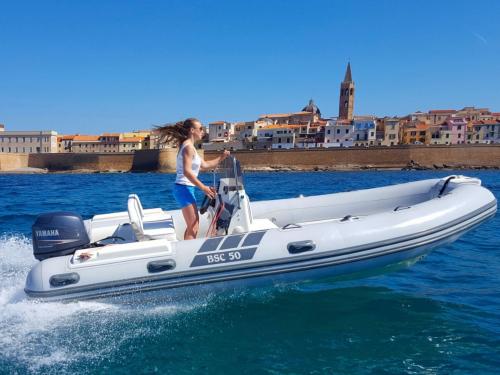 Girl in dinghy at the entrance to the port of Alghero