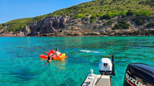 Boys swim with beach mattress in the Gulf of Alghero