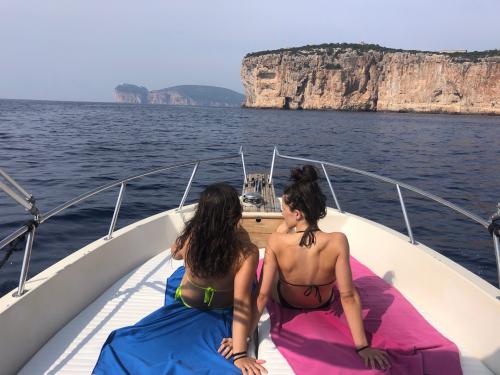 Zwei Mädchen, die auf dem Bug liegen, sind während einer Bootstour im Golf von Alghero allein unterwegs