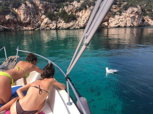 Mädchen an Bord eines Bootes an der Küste von Alghero füttern eine Möwe
