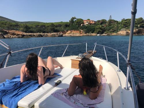 Girls lying on the bow during a stop on a boat tour in the Gulf of Alghero