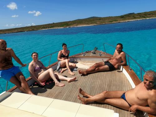 Group of friends relaxing at the bow in a wooden gozzo in the Gulf of Asinara