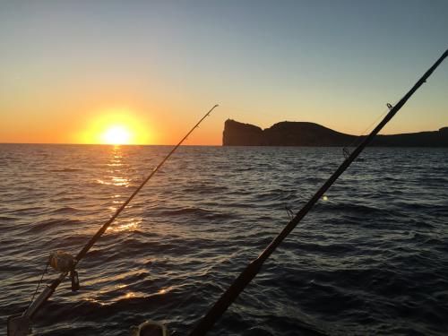 Angeln von einem Boot aus bei Sonnenuntergang auf Capocaccia während eines Ausflugs