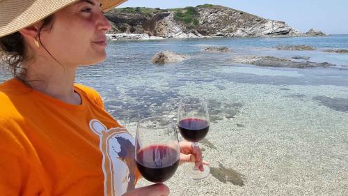 Fille avec deux verres de vin rouge sur une plage de Nurra