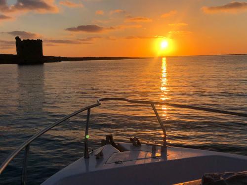 Puesta de sol en barco frente a la torre de La Pelosa