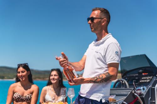 Chicas con patrón durante un aperitivo en una lancha neumática en el Golfo de Alghero