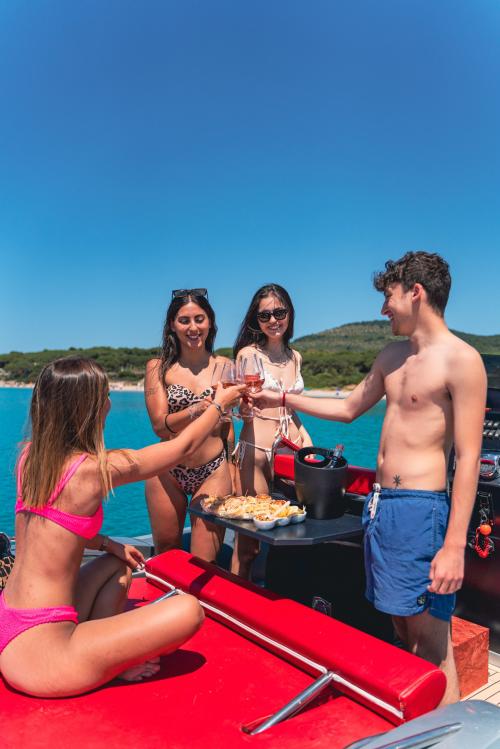 Ragazzi fanno brindisi sopra il gommone nel Golfo di Alghero