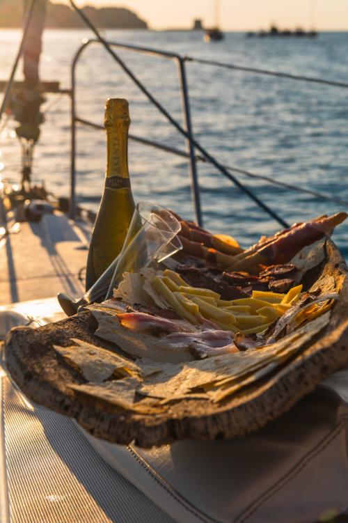 Aperitivo con vino bianco al tramonto a Stintino in barca a vela