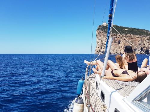 Ragazze a prua vicino Capo Caccia durante escursione in barca