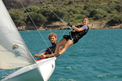 Boy and girl on board a small sailboat sailing in La Maddalena