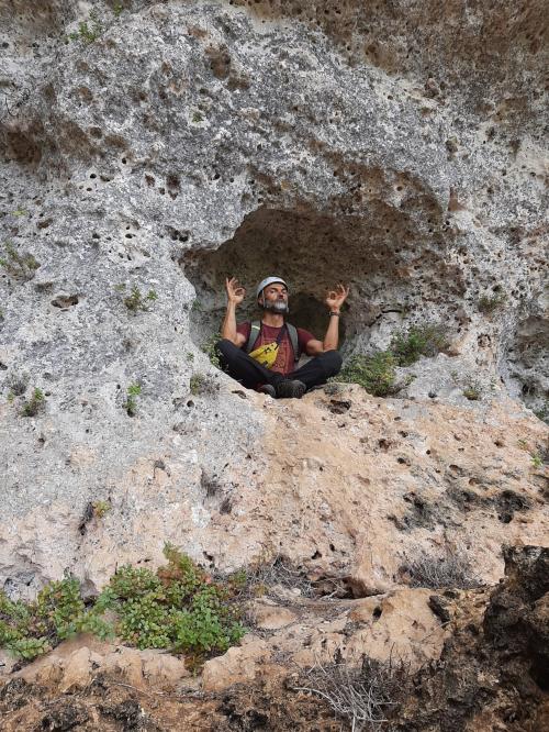 Guida in posizione di yoga dentro una piccola grotta nell'altopiano di Giorrè
