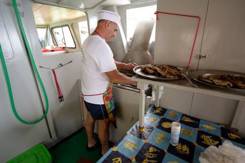 Fischer bereitet Fischmittagessen per Boot im Golf von Orosei zu