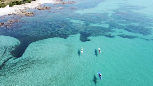 Foto panoramica della costa di Biderosa con escursionisti in kayak che pagaiano tra acque limpide in cui fare snorkeling