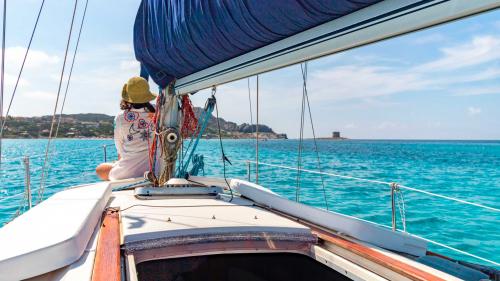 Una ragazza a prua a bordo di Equinoxe a largo della spiagge de La Pelosa