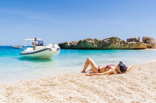 Turista si rilassa in spiaggia nel Golfo di Orosei durante tour in gommone di una giornata intera