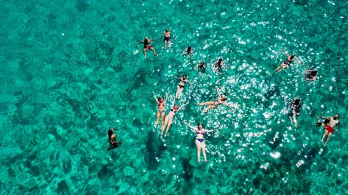 People bathe in the blue water of the La Maddalena Archipelago