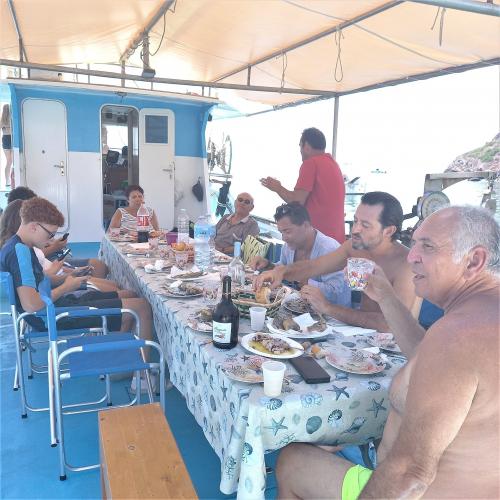 <p>Touristen an Bord eines Bootes während des Mittagessens mit Fang des Tages mit Töpfen in Alghero</p><p><br></p>