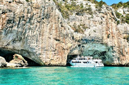 Grotta e falesia a picco sul mare nel Golfo di Orosei e motonave