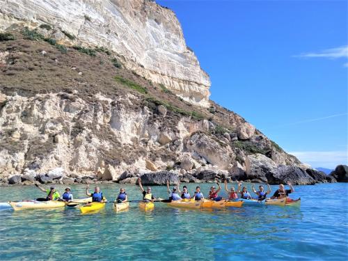 Gruppo di escursionisti in kayak nel Golfo di Cagliari tra mare cristallino e falesie a picco sul mare