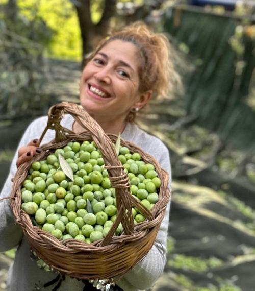 Frau zeigt Oliven im Korb