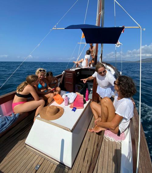 Participants relax on a vintage boat in the Gulf of Alghero