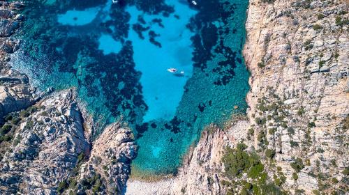 Draufsicht auf ein Boot, das vor einer Insel im Archipel von La Maddalena vor Anker liegt